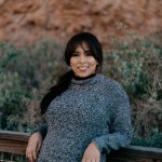 woman-in-grey-sweater-smiles-and-leans-against-a-railing